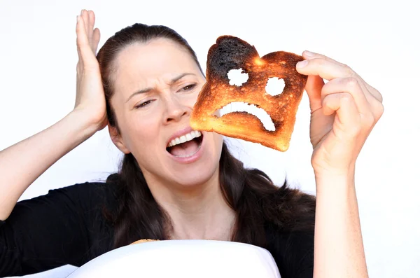 Frau schreit verbranntes Toastbrot an — Stockfoto