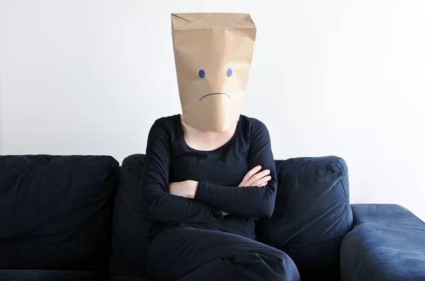 Анонимная грустная женщина сидит на диване одна — стоковое фото
