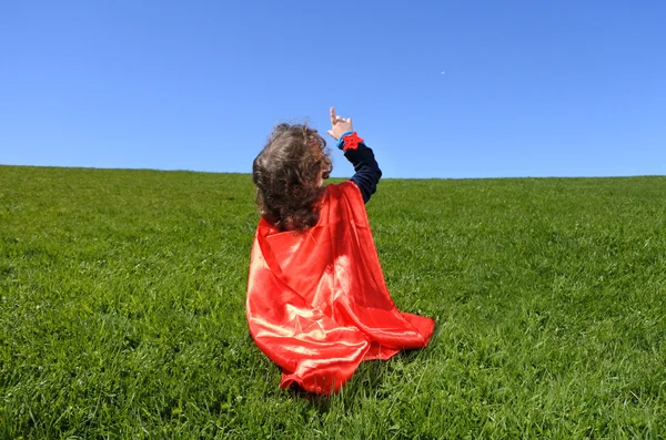 Superhéros bambin pointe vers ciel bleu dramatique — Photo