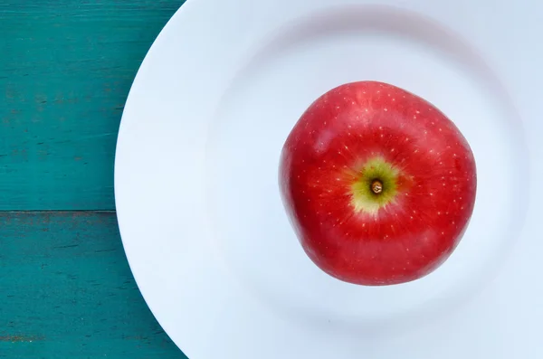 Vista plana de una manzana roja fresca servida en un plato blanco — Foto de Stock