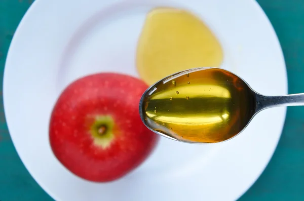 Cucchiaio pieno di miele sopra il piatto di mele e miele — Foto Stock