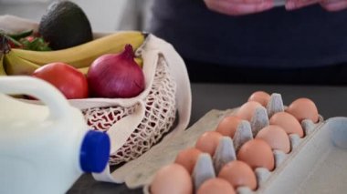 Kadın ev mutfağında alışveriş listesine bakıyor. 