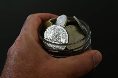 Emekli bir insan, kötü günler için sakladığı bir kavanoz dolusu Avustralya parası tutuyor..