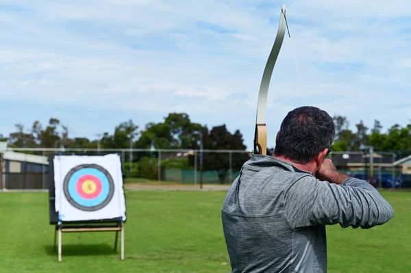 弓箭手将箭对准室外的目标 射箭是指用弓箭射箭的艺术 练习和技巧 — 图库照片