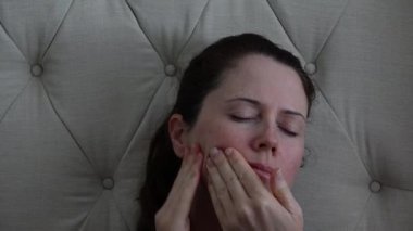 Yetişkin bir kadın (30-40 yaş) yüzüne masaj yapar.