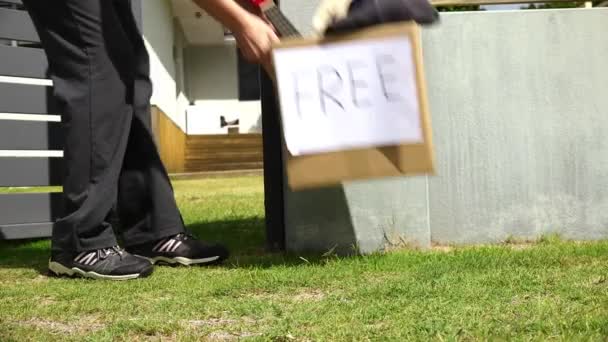 无法辨认的成年女子把家里的私人物品送出 放在家里前院门口装有免费标识的纸板箱里 — 图库视频影像