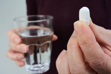 Bir bardak suyla ilaç hapını tutan kadınların ellerini kapatın..