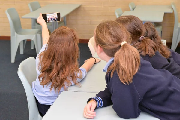 一群淘气的女学生在教室里拿着手机自拍 — 图库照片