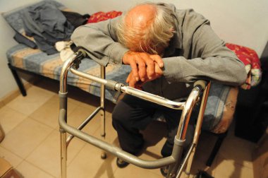 TEL AVIV - 22 Nisan 2009: Yatağında yalnız oturan zavallı yaşlı adam. İsrail 'deki yoksulluk özellikle bekar anneleri, yaşlıları, Ortodoks Yahudi cemaatlerini ve Arap toplumlarını etkiliyor..