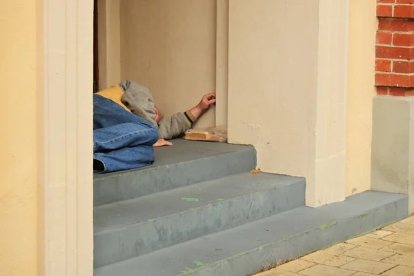 ビルのドアのステップに横たわっている認識できないホームレスの人 — ストック写真