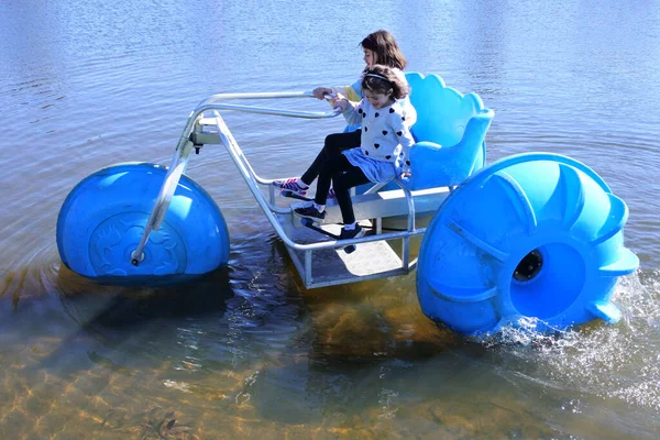 湖の水の上に大きなホイールアクアバイク水三輪車に乗って2人の若い女の子の姉妹 12と7 の空中ビュー ストックフォト