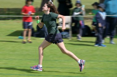 Genç bir kızın hareket bulanıklığı (11-12 yaş) çimenlerde hızla koşarken açık havada.