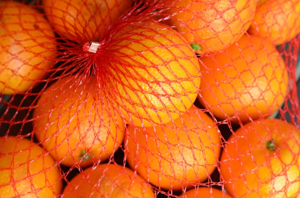 Laranjas laranja frescas em rede de plástico — Fotografia de Stock