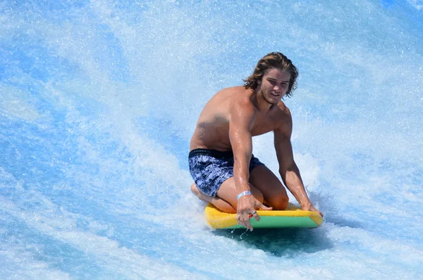 Muž na Flowrider jezdit surfovat palubě — Stock fotografie