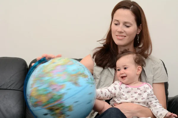 Mãe e bebê procuram e examinam o globo — Fotografia de Stock