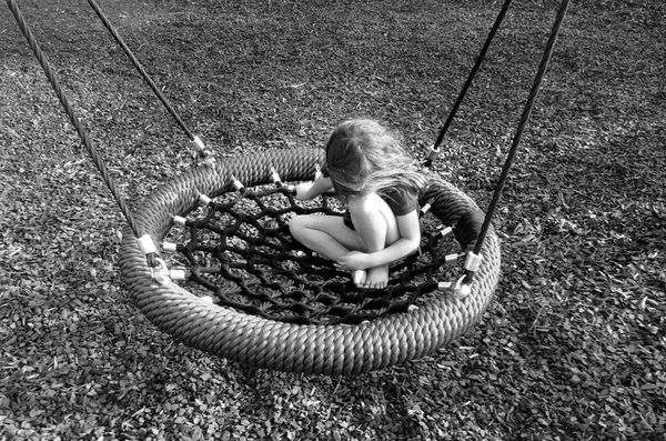 Menina triste em um balanço no playground — Fotografia de Stock