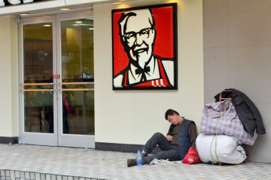 Chinese homeless on sit outside KFC fast food restaurant clipart