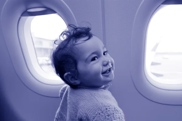 Baby looks out from the airplane window — стоковое фото