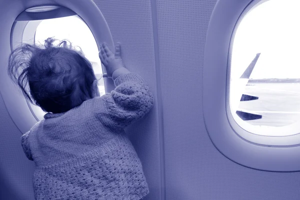 Baby looks out from the airplane window — стоковое фото