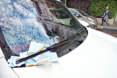 Parking ticket placed under windshield wiper of a car  clipart