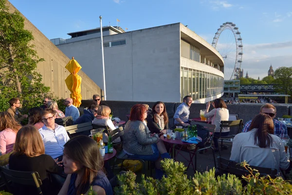 People dining outside the Royal Festival Hall in with London Eye — стокове фото