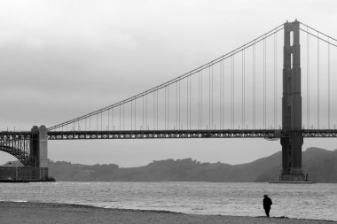 One man walks on the beach under the Golden Gate Bridge in San F