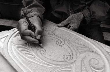 Maori man hands drawing patterns of Maori Wood carving