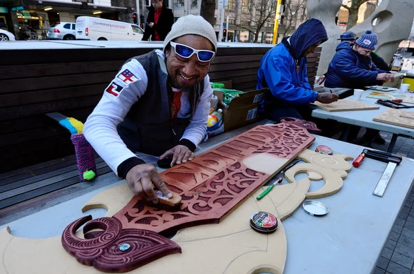 Homme maori peignant une sculpture sur bois maori — Photo