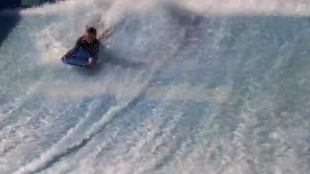 Młody człowiek jeździć na desce surfingowej na FlowRider — Wideo stockowe