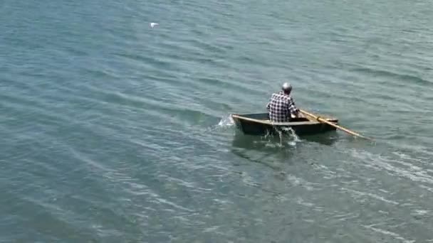 Homem rema um barco de linha no mar — Vídeo de Stock