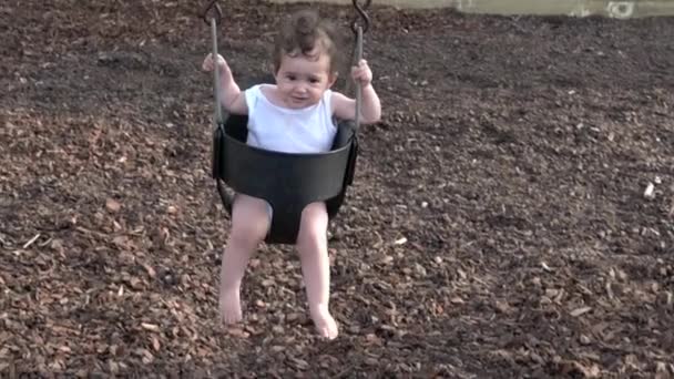 Niña en un columpio en el patio de recreo — Vídeos de Stock