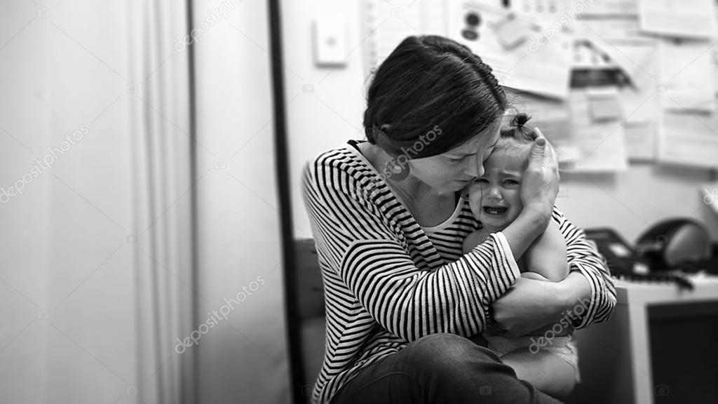 Young mother hugs a crying toddler in hospital