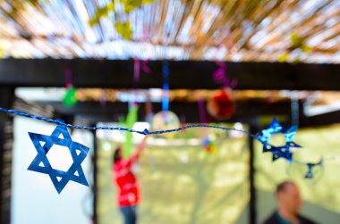 Jewish family decorating Sukkah for the Jewish festival of Sukko clipart