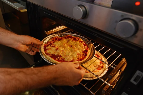 Handen uitstappen van de zelfgemaakte pizza oven — Stockfoto