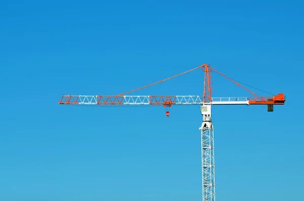 Profile of a red and white Tower crane against blue sky — Stock Photo, Image