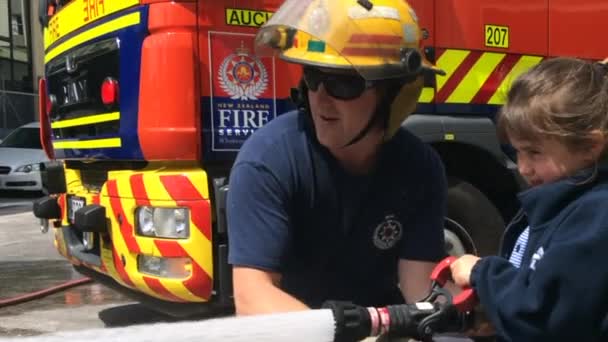 Пожарный и ребенок держат шланг — стоковое видео