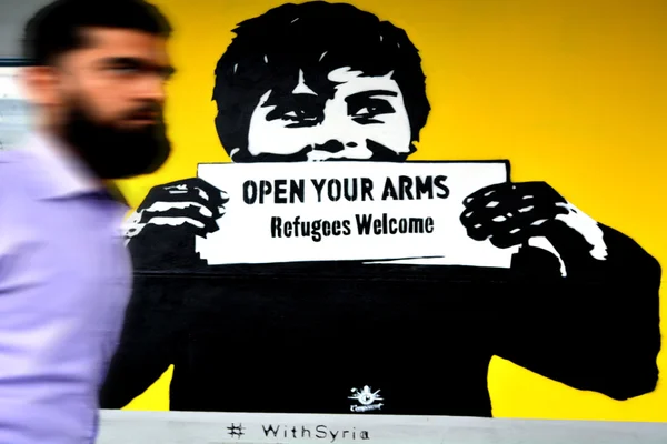 Omul din Orientul Mijlociu trece pe lângă Graffiti: "Refugiații bine ați venit " — Fotografie, imagine de stoc