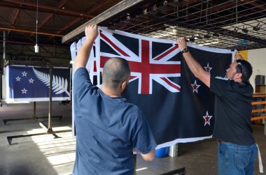 Workers hang a print of the National New Zealand flag clipart