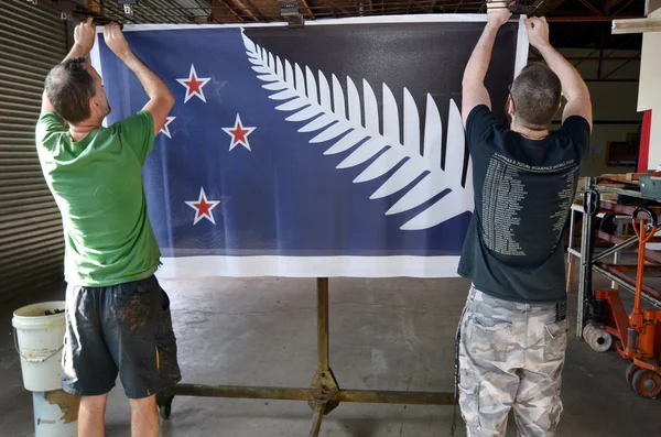 Workers hang aprint of the Silver Fern (Black, White and Blue) f — Stock Photo, Image