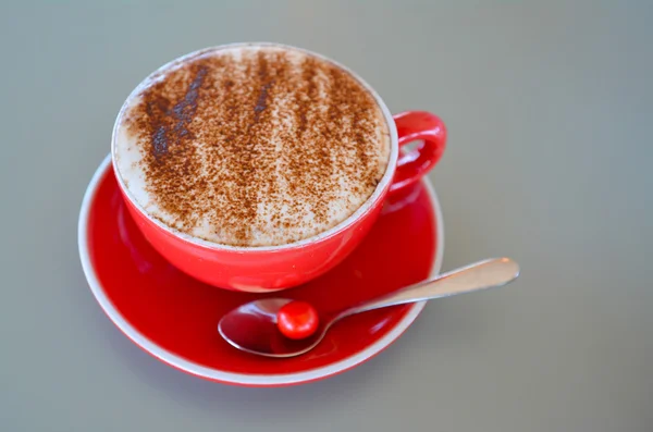 Καπουτσίνο καφέ τέχνης σερβίρεται σε μια κούπα κόκκινο — Φωτογραφία Αρχείου