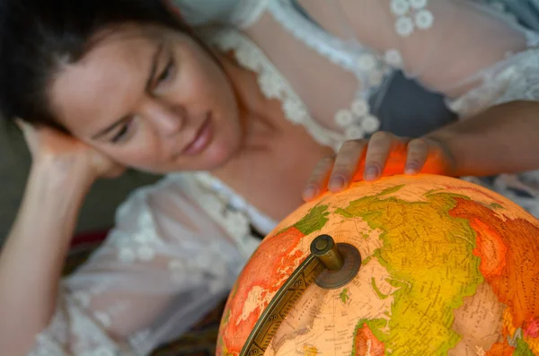 Giovane donna in cerca di una destinazione di viaggio su un globo vintage — Foto Stock