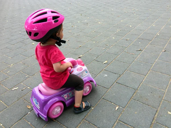 Kleines Mädchen fährt Spielzeugauto auf dem Spielplatz — Stockfoto