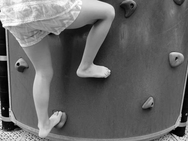 Criança subindo em uma parede de pedra do playground — Fotografia de Stock