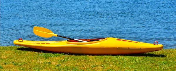 Yellow kayak on river bank — Stock Photo, Image