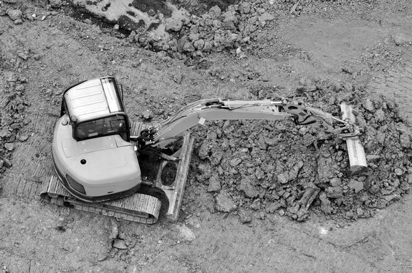 Escavadeira escava solo em um canteiro de obras — Fotografia de Stock