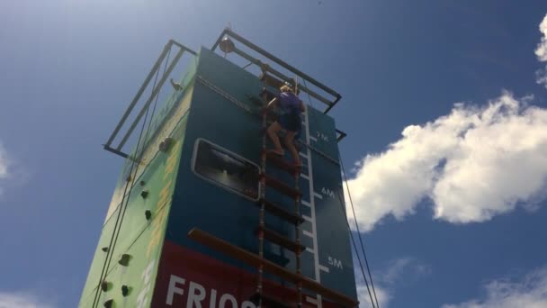 Petite fille abseiling à partir d'un mur vertical élevé escalade — Video