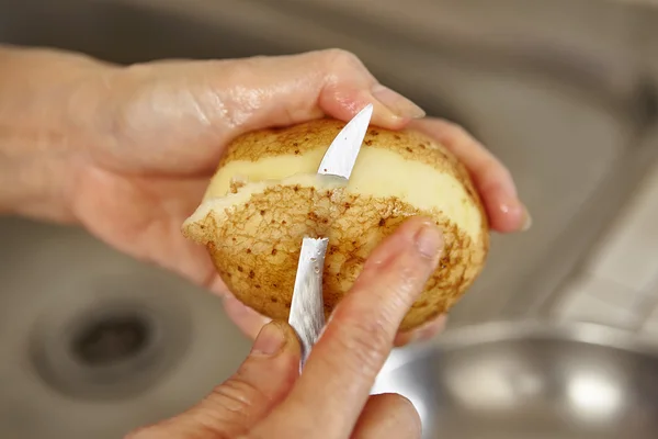 Batata é descascada com uma faca de cozinha — Fotografia de Stock