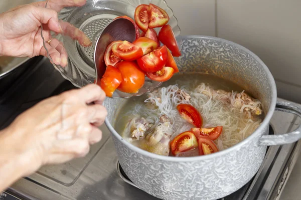 Adding tomato to the cooking in a pan — Stock Photo, Image