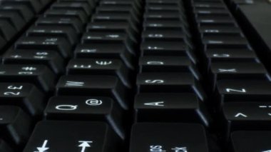 Siyah bir bilgisayarın klavyesinin tuşlarının üzerinden geçen kameranın Dolly Çekimi.