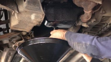 Tamir atölyesinde eski arabanın yağını değiştiriyorum.